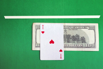 Ace of hearts and a hundred dollars as a bet underneath on a green casino bough