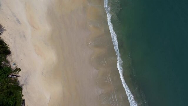 Aerial of the foamy waves of the ocean hitting the sandy Bureh Beach beach in Sierra Leone