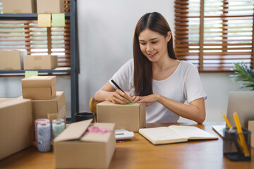 Small Asian business owner packing in the cardbox preparing parcel for delivery online selling sell Online on the Internet from home