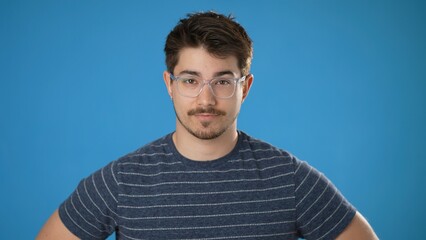 Tired exhausted displeased young man 20s wearing casual striped shirt posing isolated on blue background studio. People lifestyle concept.