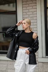 Fototapeta premium pretty woman in leather shirt jacket and cargo pants standing near building on street in Miami.