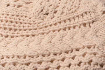 A fragment of beige knitted fabric, knitted from white sheep wool.