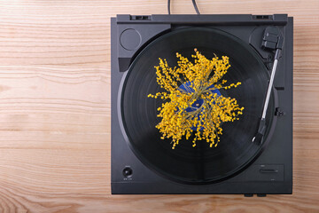 Top view of a black turntable with a playing vinyl record, on which, in place of the label, lies a...
