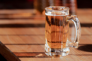 Chilled beer. A glass of beer. A low-alcohol drink. Quench your thirst. Wooden table. A glass of cold beer on a wooden table on a sunny day.