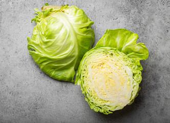 Fresh raw organic farm cabbage cut in half on grey rustic stone background top view, healthy...