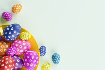 Yellow plate with colorful Easter eggs on pastel background