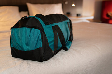 Shallow depth of field image of a small travel bag on the bed of a hotel room