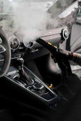 The concept of car cleaning and detailing The detailing master cleans the car interior with a hot steam cleaner Cleaning the car interior