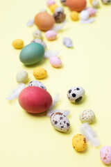 Colored eggs of different sizes on a yellow background. Symbol of the Easter holiday. Easter background. Flat lay