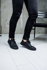 Male legs in black jeans close-up in black leather casual sneakers. Comfortable men's demi-season shoes