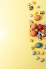 Naklejka na ściany i meble Painted multi-colored eggs different size in a yellow cardboard tray on a yellow background. Easter background, symbol. Top view