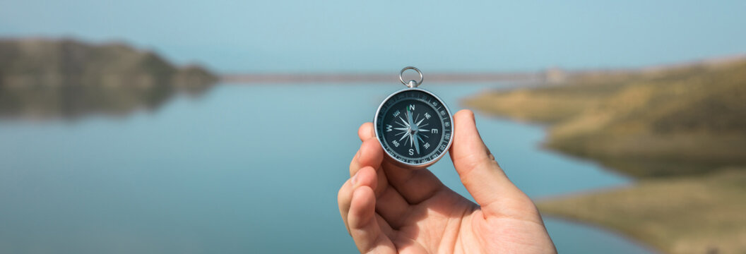 man holding compass in lake background
