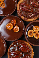 Little chocolate tarts in flat lay. Six tasty shortbread cakes with Belgian milk chocolate and nuts baked in a pastry cafe