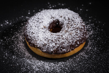 Sprinkling sugar powder on chocolate donut