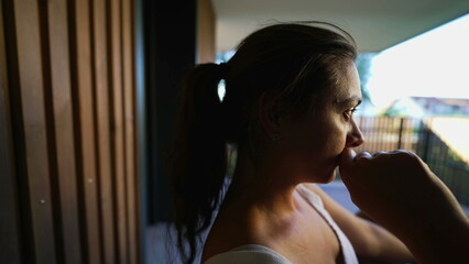 Fototapeta na wymiar Contemplative woman thinking deeply at apartment balcony. Pensive female person in her 30s with thoughtful emotion. closeup face serious expression