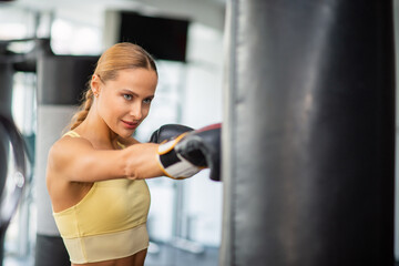 Fototapeta premium Woman training on the punching bag in a gym