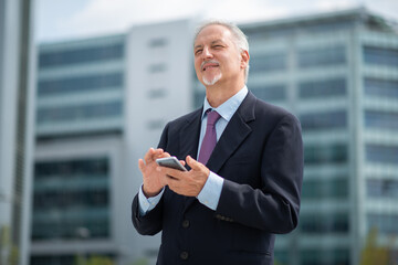 Portrait of a smiling senior businessman using his mobile phone