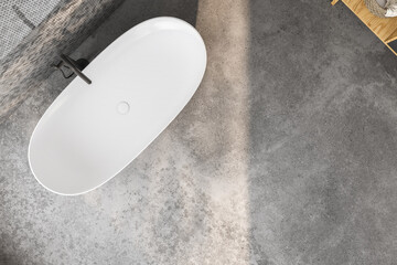 Top view of white bathtub on concrete floor in bathroom. 3d rendering