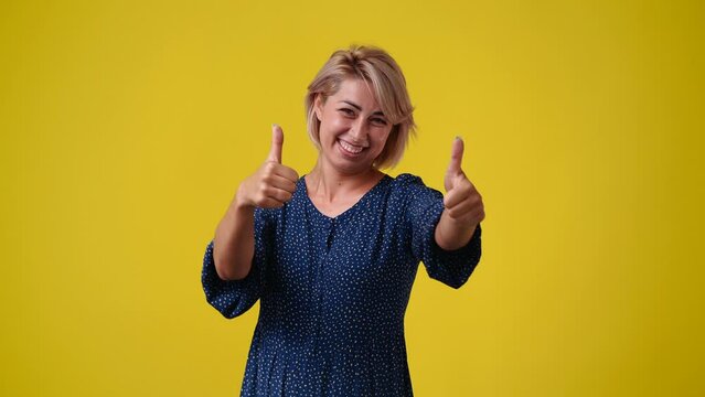 4k video of one woman thowing thumb up over yellow background.