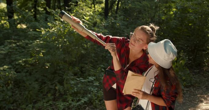 Daughter and mother hiking in forest using a map to navigate