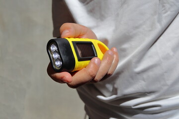 A man holds in his hands a hand-crank solar torch, for travel and hiking