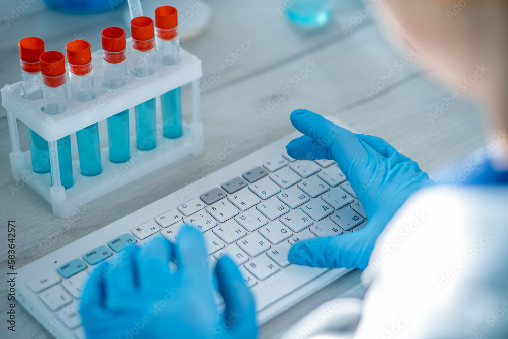 Poster a female researcher sits at a workplace in a laboratory, behind a personal computer monitor. against