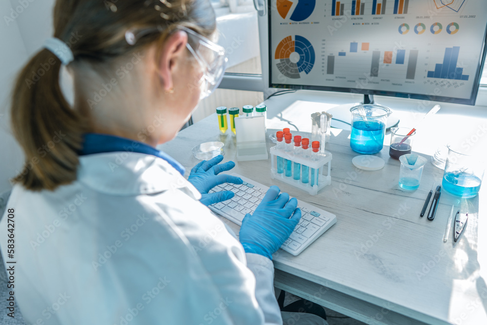 Poster a female researcher sits at a workplace in a laboratory, behind a personal computer monitor. against