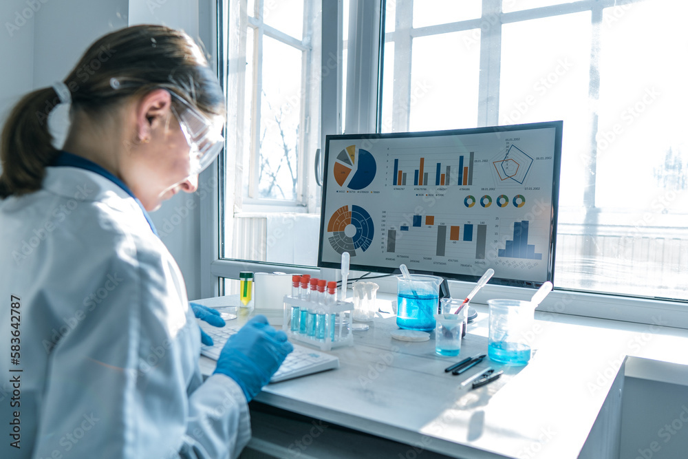Poster a female researcher sits at a workplace in a laboratory, behind a personal computer monitor. against