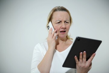  woman Seriously tense and annoyed she is standing on white background talking on phone looking at...