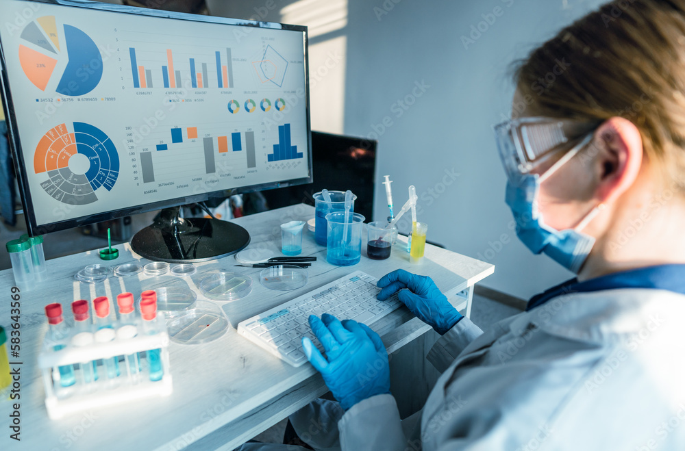 Poster a female researcher sits at a workplace in a laboratory, behind a personal computer monitor. against