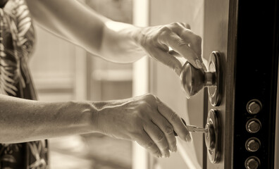 Moving to a new house. Woman hand inserting the new key in the entrance door
