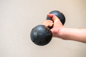 old metal dumbbell in a male hand. part close-up. home sport concept.