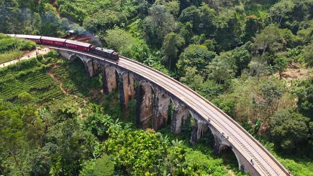 Aerial view of the old architectural nine-arch bridge in Sri Lanka with a train traveling on rails. Calm beautiful video on the background for tourism, design and advertising.