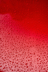 Raindrops on the red body of a car