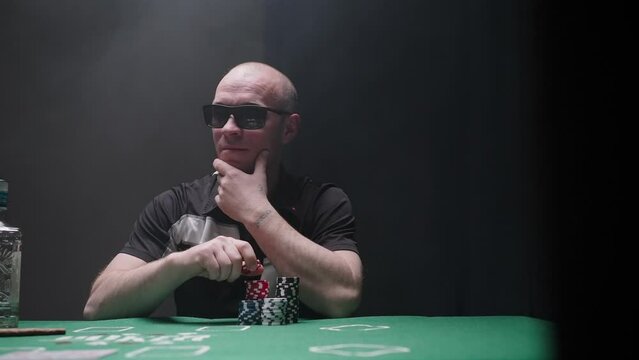 Bandit is playing poker. Action. Man is playing with poker chips. Poker player in underground club. Gambling