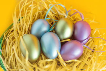 Fototapeta na wymiar Multi-colored Easter eggs in a nest on a festive orange background. The minimal concept of Easter. top view. Easter card with a copy space for text.