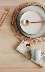 Modern ceramic tableware top view on beige wooden table with copy space.  Trendy plates, cutlery...