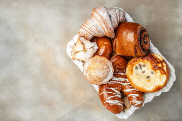 a basket of buns, croissants, and muffins, concept of homemade baking, place for text, top view