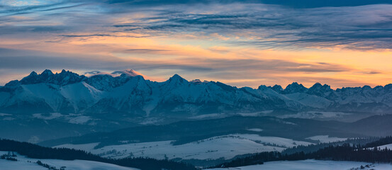 winter panorama of the Tatras against the background of the orange sky - obrazy, fototapety, plakaty