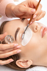 Make-up artist makes the procedure of lamination and dyeing of eyelashes to a beautiful woman in a...