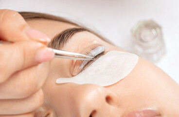 Make-up artist makes the procedure of lamination and dyeing of eyelashes to a beautiful woman in a beauty salon. Eyelash extensions. Eyelash lifting