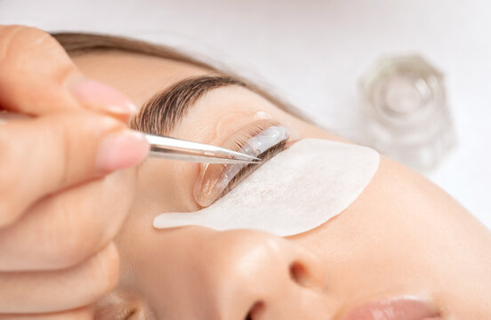 Make-up artist makes the procedure of lamination and dyeing of eyelashes to a beautiful woman in a beauty salon. Eyelash extensions. Eyelash lifting