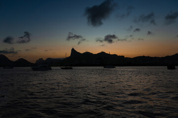 Sunset in the bay of Guanabara, cove and beaches of Rio de Janeiro, Brazil with its buildings, boats and landscape. Christ the Redeemer on top of Corcovado. Reflection of the sky in the sea