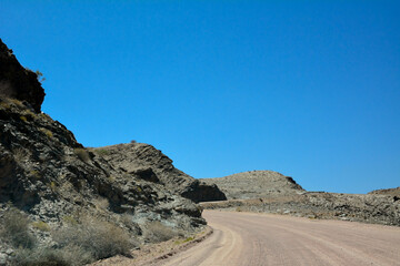 A lonely asphalt road in the desert in perspective against a blue sky