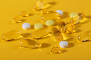 Diet, nutrition, healthy eating concept. Assorted Oil filled yellow softgels capsules and pills of food supplements on yellow background with trendy shadows and reflections