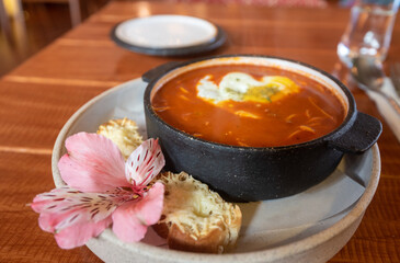 A delicious bowl of Peruvian sopa criolla and sourcream with slices of cheese bread, adorned with a flower