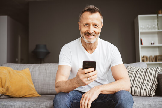 Happy Senior Man on Sofa with Smartphone