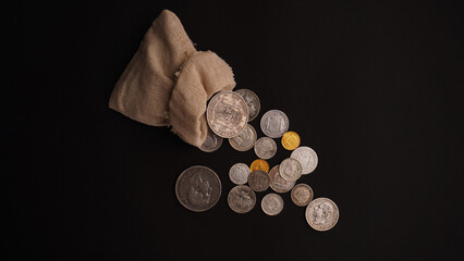  a bag from which old silver and gold coins are poured, on a black background  