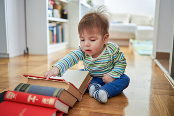 Cute baby sitting and looking at a large book.