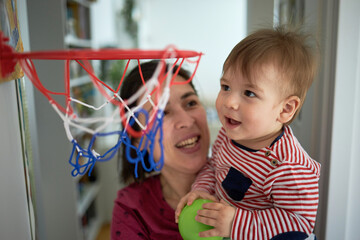Adorable and happy baby boy playing with basketball with mom